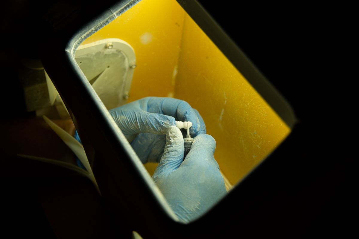 A dental technician working on a prosthetic restoration.