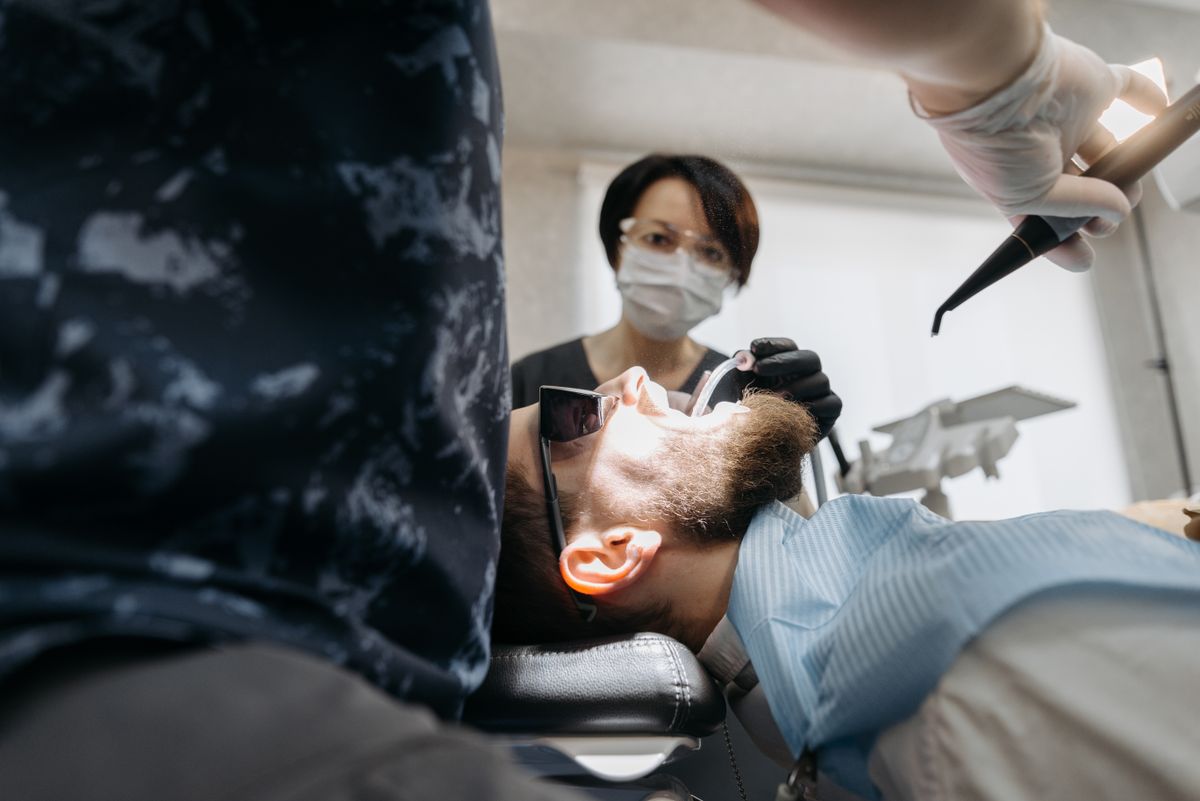 A dentist examining a patientââ‚¬â„¢s mouth in a treatment chair.